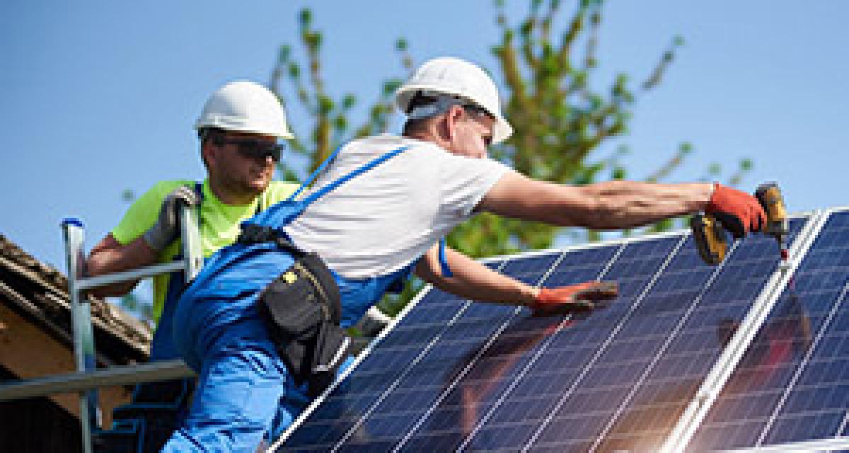 Technici připevňují solární panely na střechu domu
